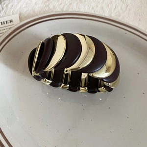 Detail view of wavy stretch bracelet with dark brown resin and gold metal links