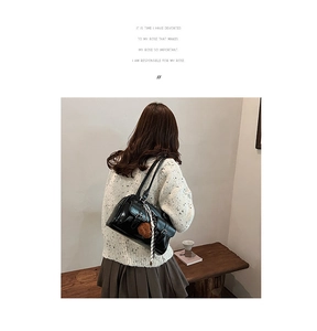 Detail of black leather bowling bag with decorative scarf and plush keychain charm