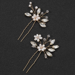 Gold bridal hair pins with white pearls and crystal leaves on a black background