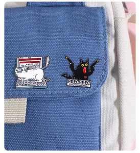 Close-up of cute cartoon cat enamel pins with humorous slogans on a canvas bag