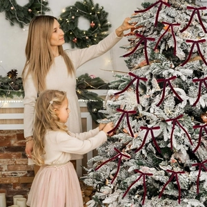 Deep red velvet Christmas tree bows shown in a cozy mother and daughter home scene