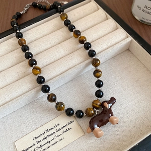 Close-up of beaded tiger eye necklace with brown dachshund pendant in jewelry box