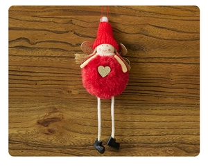 Detail of red plush angel Christmas ornament with gold heart and wings on wood background