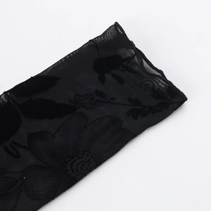 Détail du tissu en maille noire transparente avec motifs floraux floqués 3D élégants