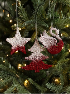 Detail of flocked red and white Christmas ornaments with glitter on a lit tree