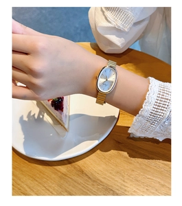 Elegant gold vintage style watch with oval dial worn during a classy afternoon tea