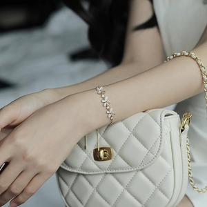 Elegant gold bracelet with cat eye stone floral charms and rhinestones worn on wrist
