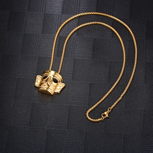 Macro detail of golden Sanxingdui mask pendant on box chain over black textured background