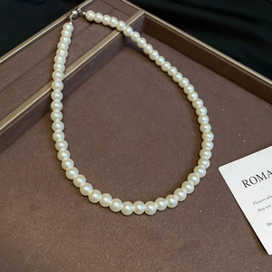 Elegant round cream pearl necklace with silver clasp on luxury dark velvet jewelry tray