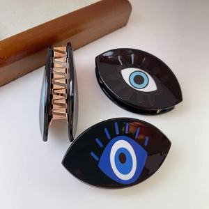 Three-piece set of black acetate shark clips featuring blue evil eye patterns and gold teeth