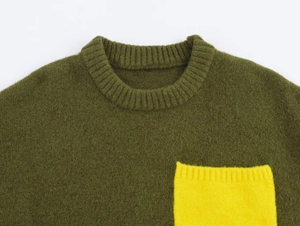 Detail of olive green knit sweater featuring a vibrant yellow chest pocket and ribbed crewneck