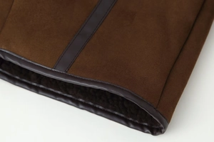 Dettaglio cappotto scamosciato marrone scuro con fodera in pelliccia sintetica e bordi in pelle