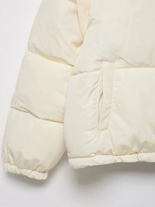 Detailed close-up of cream quilted puffer jacket featuring elastic cuffs and side pockets