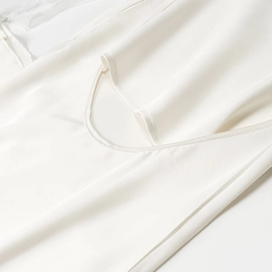 Detailed macro view of white satin dress showing smooth fabric texture and cowl neckline