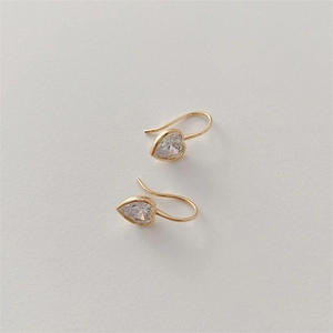 Close-up of golden heart-shaped hook earrings with sparkling clear cubic zirconia