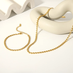 Detail of golden stainless steel heart-link necklace and bracelet set on studio props