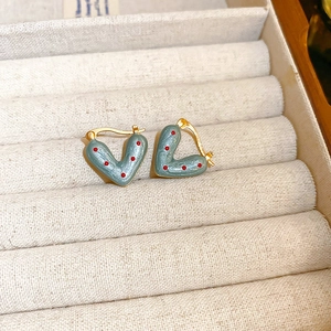 Detail of heart-shaped blue earrings with red polka dots in a white jewelry box