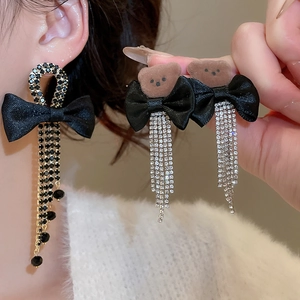 Detail of long bowknot earrings with bear head motifs and sparkling crystal tassels