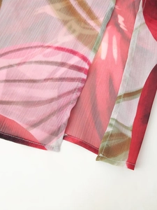 Détail du tissu mousseline à fleurs rouges montrant la transparence et les coutures