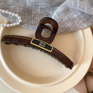 Détail de la pince à cheveux en résine brune avec plaque dorée du logo min min