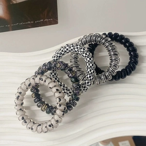 Set of five spiral telephone cord hair ties in assorted patterns on white pedestal
