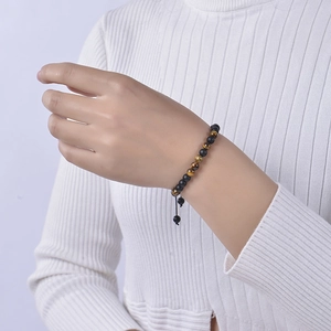 Detailed close-up of tiger eye and matte black beaded bracelet with adjustable woven cord