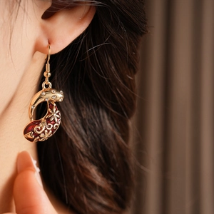 Detail of vintage gold fish earrings with red enamel patterns and sparkling crystals