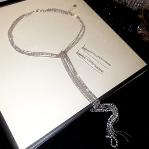 Dettaglio di parure di gioielli con collana a nappe multistrato e orecchini con strass