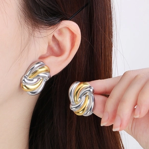 Close-up of dual-tone 18K gold plated twisted knot earrings worn by a model