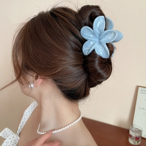 Détail d'une grande pince à cheveux fleur bleu clair à effet marbré sur une coiffure