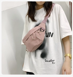 Pink nylon crossbody bag with adjustable strap and zipper detail shown on a model