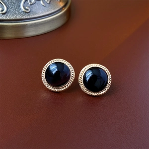 Macro shot of vintage round cat eye stud earrings with gold rim on brown leather
