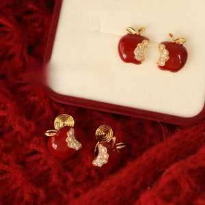 Macro shot of red apple earrings with zircon inlay in a luxurious gift box