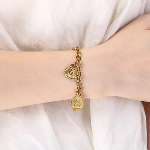 Detail of 18K gold-plated chunky chain bracelet with heart lock and angel coin charms