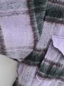 Detail view of the brushed purple plaid fabric and flap pocket on a winter coat