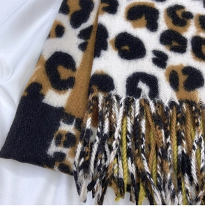 Detailed macro view of leopard print scarf fabric texture and long tassels