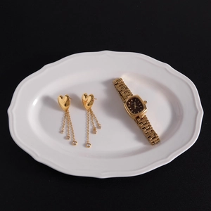 Golden heart stud earrings with dangling rhinestone tassels in a ceramic tray