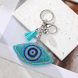 Close-up of heart-shaped evil eye pendant with blue crystals and silk tassel detail