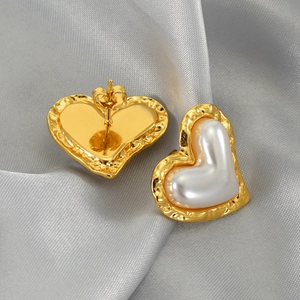 Elegant gold-tone heart-shaped pearl earrings with hammered metal texture on silk background