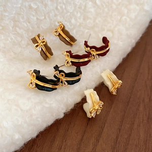 Close-up of C-shaped bow earrings in brown, wine red, black, and beige with crystals