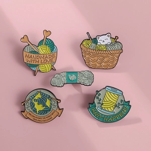 Detailed view of handmade cat enamel pins with wool yarn and knitting themed motifs