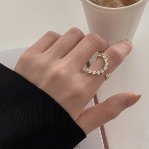 Close-up of a gold open ring with curved crystals on a model finger in a lifestyle setting