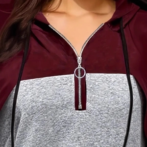 Detail of color-block hoodie with burgundy and grey patchwork and silver ring zipper
