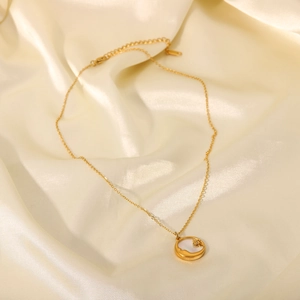 Detailed shot of 18K gold star and moon pendant on white mother-of-pearl and silk