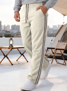 Close-up of beige joggers with side stripes and drawstring waist in a lifestyle setting