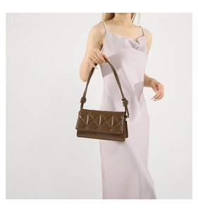 Detail of dark brown quilted shoulder bag with knotted strap on a silk dress