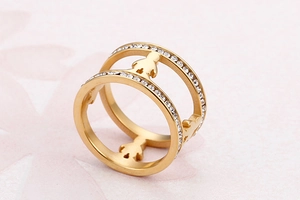 Macro detail of golden double-band ring with pavé crystals and hollow figure charms