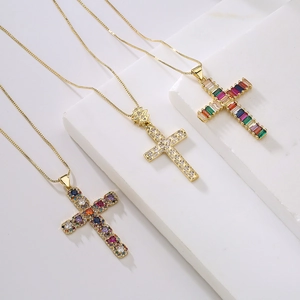 Three gold cross necklaces with rainbow zircon and crystal pendants on a white background