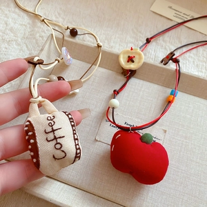 Detail of handmade fabric charms featuring red apple and coffee cup with beads
