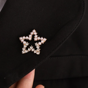 Elegant five-pointed star brooch with pearls and crystals pinned on a black suit lapel